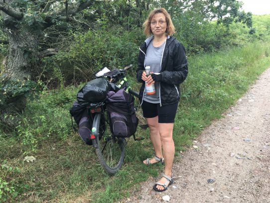 Rin in die Klamotten, raus aus … Frau neben Fahrrad
