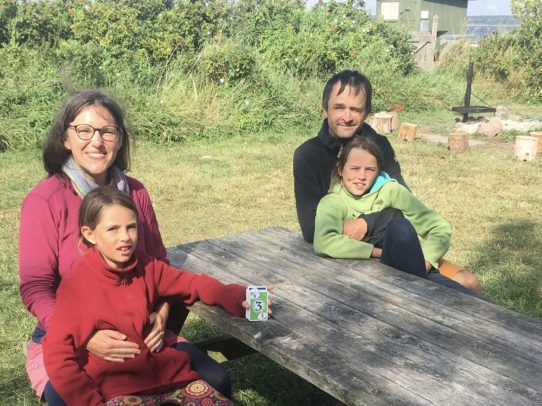 5D1B1469-8F0B-47BF-A25B-4A4564C3DE4C Familie mit zwei Kindern draußen am Tisch.